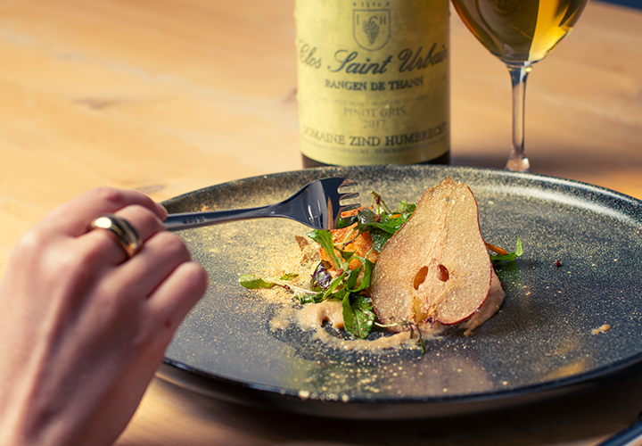 Une main saisit un fromage de chèvre aux côtés d'une bouteille de vin primée. 